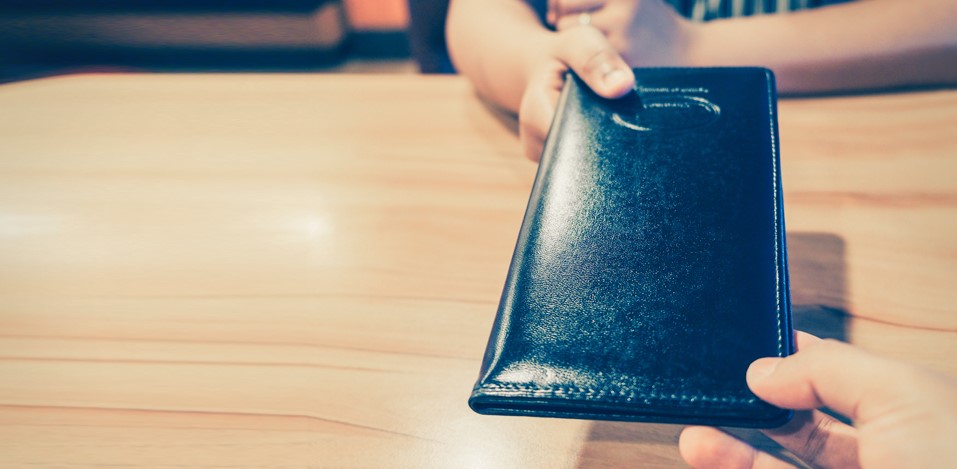用餐時把銀包遞給對方,呈現主動分擔餐費或請客以表達感謝的情境
